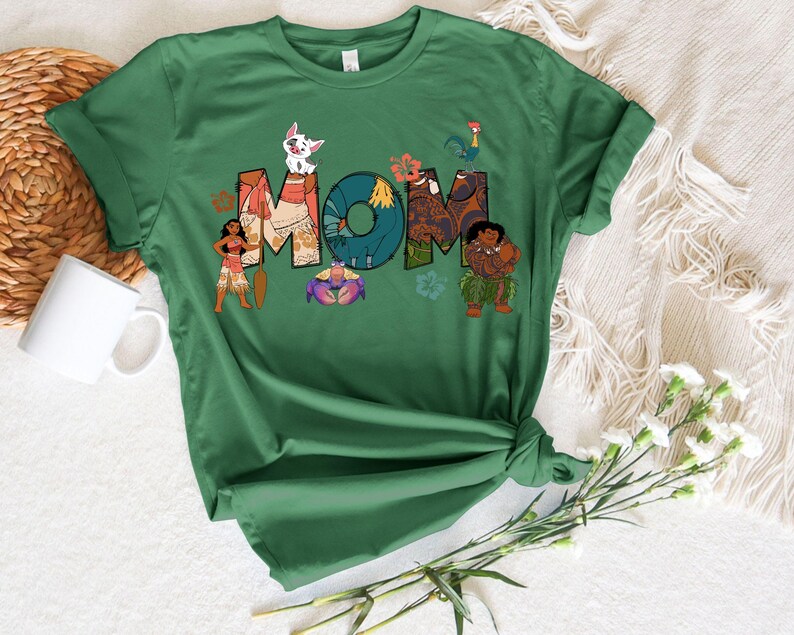 May include: Green t-shirt featuring a graphic of characters from the film Moana spelling out the word "MOM".