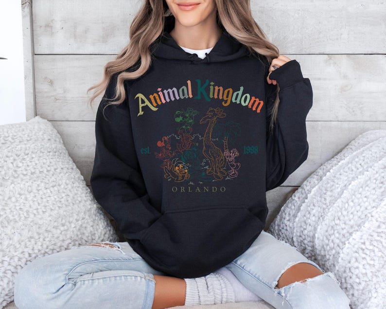 May include: Black hooded sweatshirt with the text "Animal Kingdom" in colorful lettering. The design includes a giraffe and other animal illustrations, with "Orlando" and "1998" printed below. The sweatshirt has a front pocket.