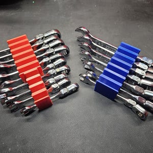 May include: Two sets of wrenches organized in a red and blue tool holder. The wrenches are silver and have a shiny finish. The tool holders are made of plastic and have a grid pattern.