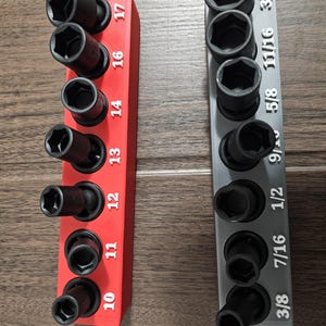May include: Two socket organizers, one red and one gray, each holding black sockets. The red organizer has sizes 10 through 17, while the gray organizer has sizes 3/8 through 1/2 and 7/16 and 11/16. The sockets are arranged vertically.