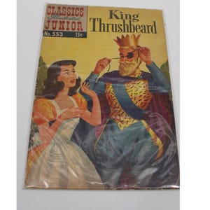 May include: A vintage comic book cover featuring a king with a long beard and an eyepatch. He is wearing a gold crown and a colorful robe. A woman with long brown hair is standing next to him. The comic book is titled "King Thrushbeard" and is from the "Classics Illustrated Junior" series. The cover is in good condition with some wear and tear.
