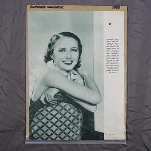 May include: Black and white photo of Barbara Stanwyck, a famous actress, from 1933. She is wearing a dark dress and sitting in a chair with a patterned fabric. The photo is from a magazine and includes text about her career.
