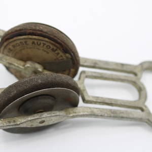 May include: A silver metal tool with two round, brown, abrasive wheels. The wheels are labeled "El Rose Automatic".