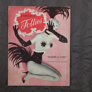 May include: A pink and white program for the "Fabulous Follies" show, featuring a woman in a black and white costume with a feather boa. The show is at the Prince of Wales Theatre and is called "Plaisir de Paris".