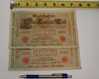 May include: Two vintage German 1000 Mark banknotes from 1910. The banknotes are printed on paper with a light brown background and feature intricate floral designs. The text "Reichsbanknote. Ein Tausend Mark" is printed in black ink. The banknotes are in good condition and have been well-preserved.
