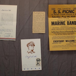 May include: A collection of vintage ephemera, including a patriotic poem with an American flag, a newspaper clipping, a postcard with a portrait, and a yellow flyer advertising a 1939 picnic featuring a Marine Band.