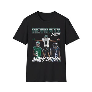 May include: Black t-shirt featuring a graphic of football player DeVonta Smith. The design includes the text "DEVONTA SMITH" above images of the player in different uniforms, with the text "SKINNY BATMAN" below.