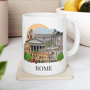 May include: A white ceramic mug featuring a colourful illustration of iconic Roman landmarks including the Colosseum, the Pantheon, and the Altare della Patria, with a small red scooter and the word ROME printed in black at the bottom centre.