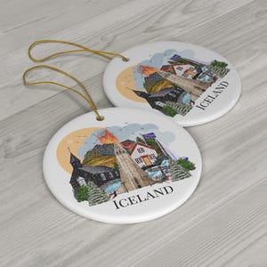 Colourful double sided Iceland ornament featuring a colourful illustration of popular Icelandic Landmarks like the Reykjavik church, waterfall, volcano, black sand beach, elephant rock, puffins and more! The text "ICELAND" is printed on under the design.