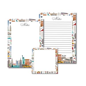May include: Three notepads featuring a New York City design. The notepads are white with a border of NYC landmarks, including the Statue of Liberty, Empire State Building, and yellow cabs. The word "Notes" is written in cursive.
