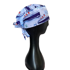 May include: A blue and white surgical scrub hat with a print of a ship. The hat has a tie on the back.