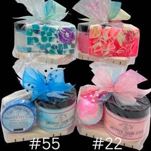 May include: Four gift sets of bath products, each wrapped in cellophane and tied with a ribbon. Sets include soaps, sugar scrubs, and shower steamers. The soaps are various colors and designs. The sugar scrubs are in jars with black lids. The text "#55" and "#22" are at the bottom.