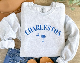 May include: Gray sweatshirt with a blue graphic of the text "CHARLESTON" in an arc with a crescent moon and a palm tree underneath.