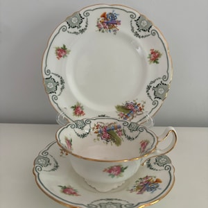 Puede incluir: Un juego de taza y platillo de té vintage con un patrón floral y ribete dorado. El juego presenta un diseño delicado con flores rosas y azules y hojas verdes.