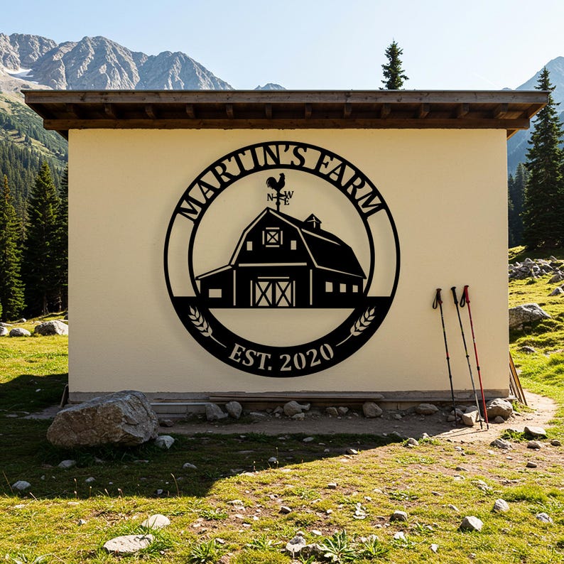 May include: A black metal sign with the words "MARTIN'S FARM" in a circular design, featuring a barn silhouette, a weathervane, and the year "EST. 2020". The sign is mounted on a beige wall, with mountains in the background.