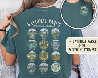 May include: A teal blue t-shirt with a graphic of 12 national parks of the Pacific Northwest. The graphic includes the names of each park and a small illustration of the park.
