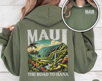 May include: A green hooded sweatshirt with a graphic print of a scenic road in Maui, Hawaii. The text "Maui The Road to Hana" is printed on the sweatshirt.