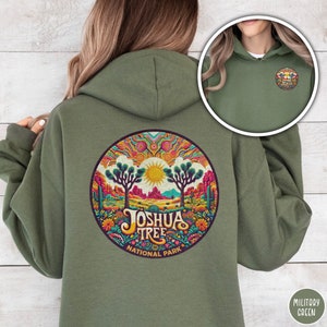 May include: A green hooded sweatshirt with a colorful Joshua Tree National Park design on the back. The design features a circle with a sunset, Joshua trees, and flowers.