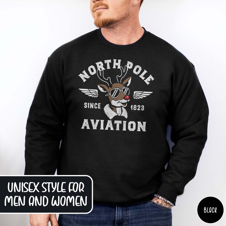May include: Black crew neck sweatshirt with a distressed graphic featuring a reindeer wearing sunglasses and the text "NORTH POLE AVIATION SINCE 1823." The sweatshirt has the text "UNISEX STYLE FOR MEN AND WOMEN" in a white box.