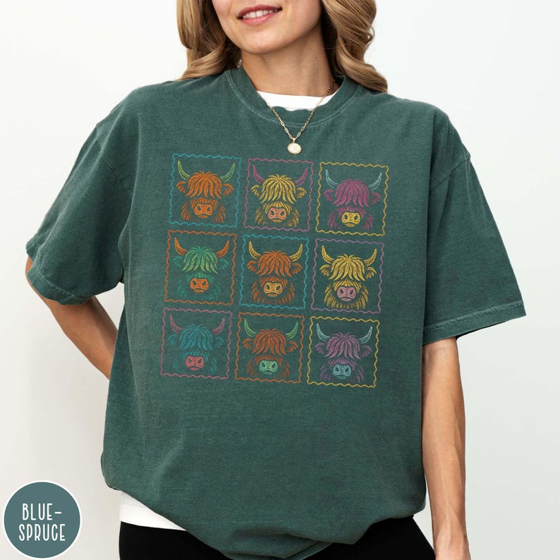 May include: A dark teal t-shirt featuring a grid of nine colorful Highland cow illustrations. Each cow is framed in a colorful, postage stamp-like border. The shirt has a relaxed fit and the text "BLUE-SPRUCE" is visible on the bottom left.