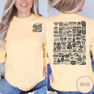 Puede incluir: Una camiseta amarilla de manga larga con un estampado gr&aacute;fico negro de todos los parques nacionales de Estados Unidos. El gr&aacute;fico incluye los nombres de cada parque y un peque&ntilde;o icono que representa el parque.