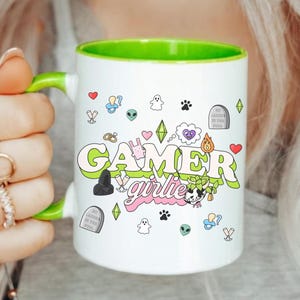 May include: A white ceramic mug with a black handle and the text "But First, Coffee" in a bold, black font. The mug is set against a blurred background, suggesting a cozy setting.