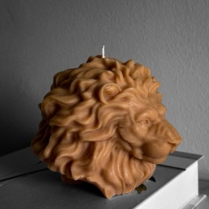 May include: A brown lion-shaped candle with a white wick. The candle is made of wax and has a detailed design.