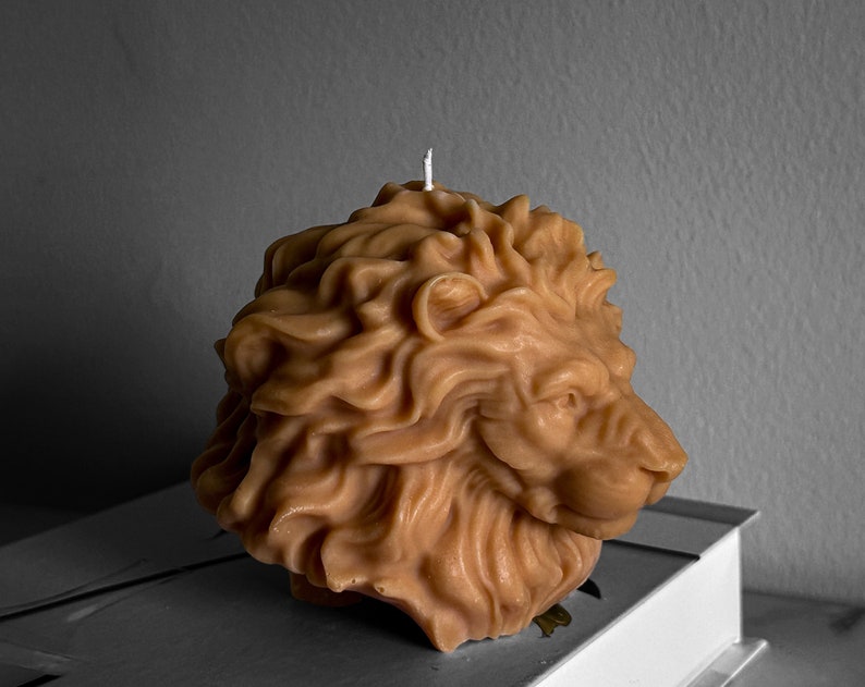 May include: A brown lion-shaped candle with a white wick. The candle is made of wax and has a detailed design.