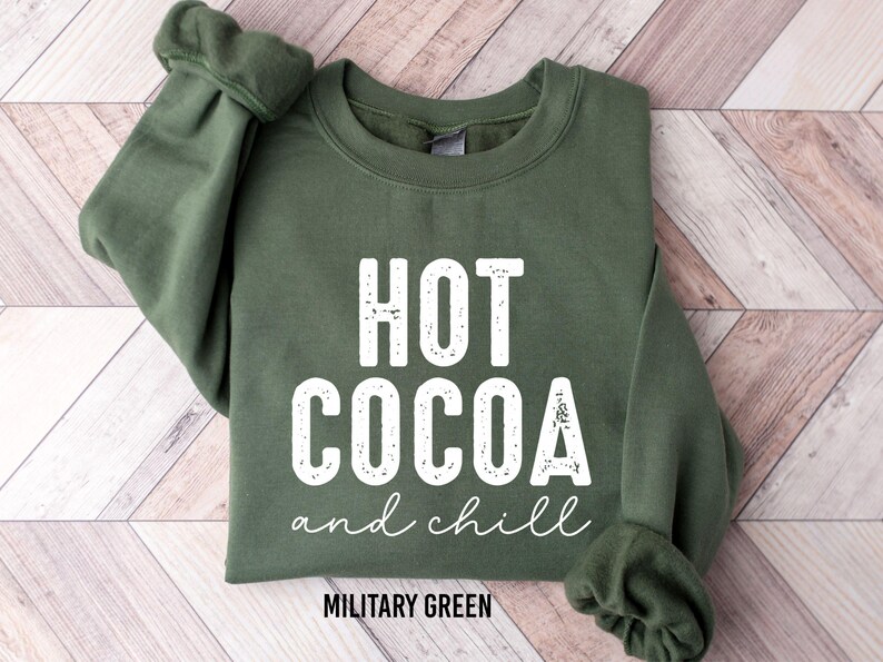 A green sweatshirt with white text that says "HOT COCOA and chill" printed on it.