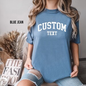 a woman sitting on a table wearing a blue tee shirt