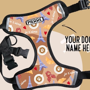 May include: A brown and black dog harness with a Parisian theme. The harness features a repeating pattern of the Eiffel Tower, coffee cups, croissants, and the phrase "je t'aime". The harness also has a black adjustable strap and a black buckle. The text "PIERRE" is printed on the harness.