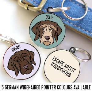Op de afbeelding: Drie gepersonaliseerde hondenhangers met illustraties van Duitse Drahthaar. De hangers zijn rond en hebben een zilveren afwerking. De eerste hanger heeft de tekst "Ollie" en een lichtblauwe achtergrond. De tweede hanger heeft de tekst "Bruno" en een lichtpaarse achtergrond. De derde hanger heeft de tekst "Escape Artist 07123456789" en een crèmekleurige achtergrond.