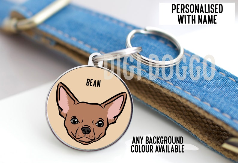 May include: A round metal pet ID tag featuring a tan background and a cartoon illustration of a brown chihuahua dog face. The name BEAN is printed in black above the dog. The tag includes a silver split ring for attachment to a blue denim collar.