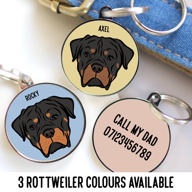 May include: Three circular metal pet ID tags with silver split rings. Two tags feature a Rottweiler illustration with the names AXEL and ROCKY. The third tag is light pink with the black text CALL MY DAD 07123456789 printed on the surface.