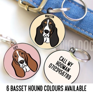 May include: Three round metal dog tags with a Basset Hound illustration and text. The tags are on a white background. The first tag has a cream background with the text "WINSTON" and a black and white Basset Hound illustration. The second tag has a pink background with the text "LUCY" and a brown and white Basset Hound illustration. The third tag has a white background with the text "CALL MY HOOMAN 07123456789".