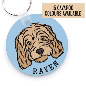May include: Round blue key chain with a cartoon illustration of a brown and white Cavapoo dog with the name "RAVEN" printed in black text.