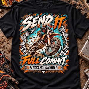 Puede incluir: Una camiseta negra con un gráfico de un piloto de motocross en una moto de cross naranja. El texto dice SEND IT, FULL COMMIT y WEEKEND WARRIOR. El diseño incluye detalles en naranja y azul, banderas a cuadros y efectos de salpicaduras de barro.