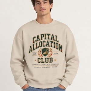 May include: A beige crewneck sweatshirt featuring a dark green and camouflage-patterned graphic on the chest. The text reads CAPITAL ALLOCATION CLUB, EST. 2026, CORPORATE FINANCE DIVISION, and INVEST OPTIMIZE GROW, with a central shield icon.