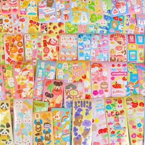 May include: A collection of colorful sticker sheets featuring various themes, including animals, food, and flowers. The stickers are on a white background and have a glossy finish.