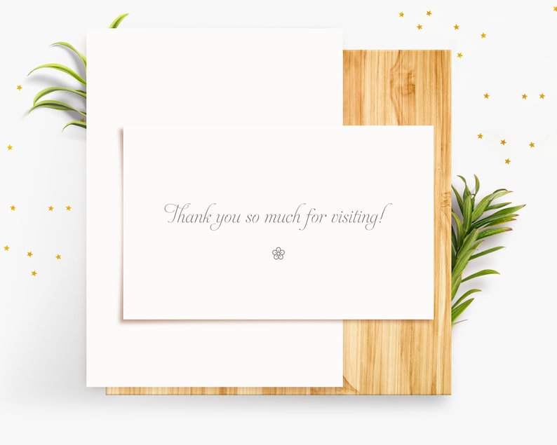 Puede incluir: Una tarjeta blanca con el texto "&iexcl;Muchas gracias por tu visita!" sobre una superficie de madera con una planta verde y purpurina dorada.