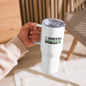 May include: White travel mug with a green and black logo that says "SG DIGITAL NOMAD" with a green play button icon.
