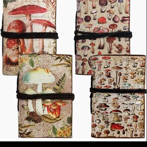 May include: Four notebooks with mushroom illustrations. The covers feature various mushroom species in shades of red, brown, and white, with botanical details. Each notebook is bound with a black cord.