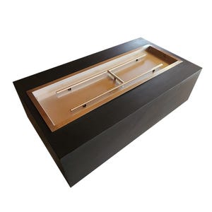 May include: Rectangular black fire pit with a stainless steel burner and a copper-colored interior. The fire pit is designed for outdoor use and has a modern, minimalist aesthetic.