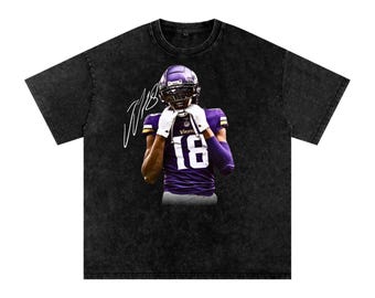 May include: Black t-shirt featuring a graphic of an American football player in a purple and white uniform with the number 18. The player is wearing a helmet and white gloves. The shirt has a distressed, vintage look.