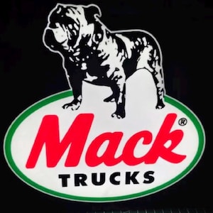 May include: A black and white image of a bulldog standing above the word "Mack" in red letters, with "TRUCKS" in black below. The logo is set on a white oval with a green border, against a black background.