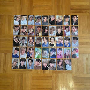 May include: A collection of 42 rectangular photo cards, each featuring a different person. The cards are arranged in a grid pattern on a wooden surface. The people in the photos have various hairstyles and are wearing different outfits.