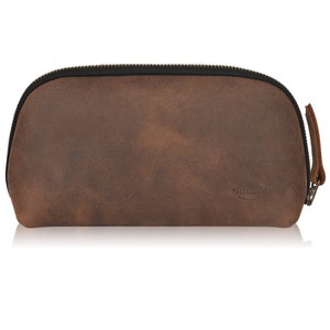 Puede incluir: Una bolsa de cuero marr&oacute;n con cremallera y un logotipo de Nubuck.