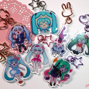 May include: A collection of seven acrylic keychains featuring various anime-style characters with teal, blue, and green hair. Each charm includes a metal clasp in shapes like stars, hearts, and bows, displaying colorful illustrations of figures in diverse outfits.