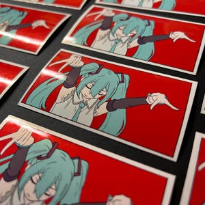 Pode incluir: Autocolantes retangulares com uma ilustra&ccedil;&atilde;o de um personagem de anime. O personagem tem rabos de cavalo turquesa, uma parte superior branca e um fundo vermelho. O personagem est&aacute; em uma pose din&acirc;mica com os bra&ccedil;os estendidos.