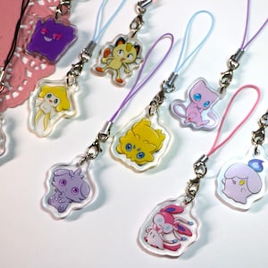 May include: A collection of nine clear acrylic charms featuring colourful cartoon character illustrations. Each charm is attached to a small metal lobster clasp and a thin, coloured nylon cord loop in shades of pink, purple, and light blue.